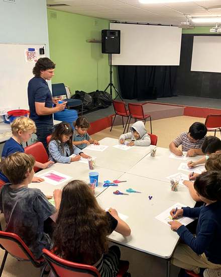 Children drawing at tables with a leader in the CalvaryKIDS room